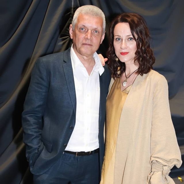 Aleksandr Galibin in a white shirt and black suit with his wife in a plancton colored dress.
